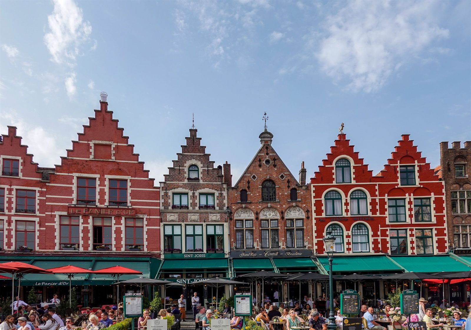 Colorful stepped-gable guild houses and cafe awnings on the Markt in Bruges, Belgium