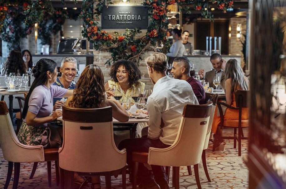 Friends laughing around a table in an Italian trattoria dining room at sea