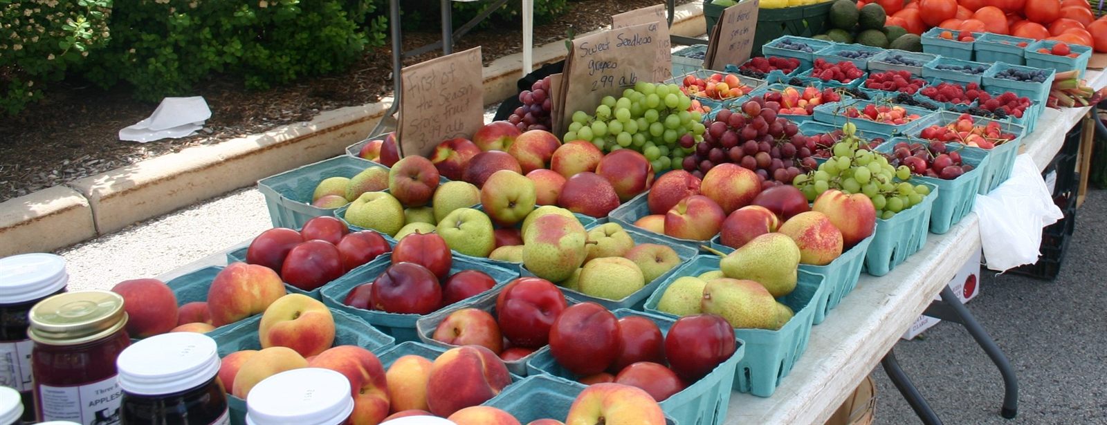 Crates of apples, peaches and grapes on an outdoor farmers market stall